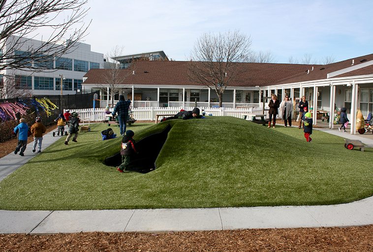 Kids playing on play mounds covered in Playground Grass Ultra by ForeverLawn at Security Benefit Academy in Topeka, Kansas